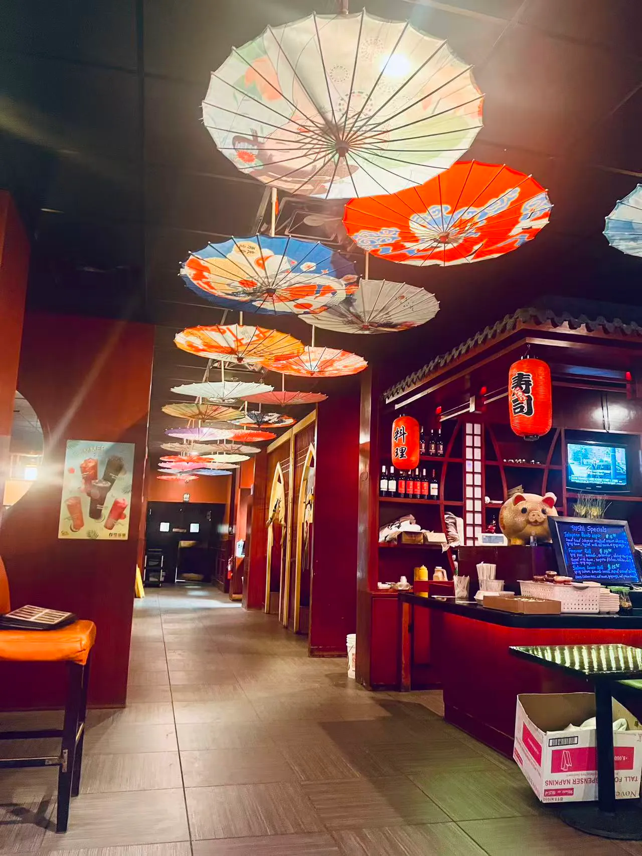 A restaurant hallway decorated with colorful Japanese paper umbrellas hanging from the ceiling and red lanterns.